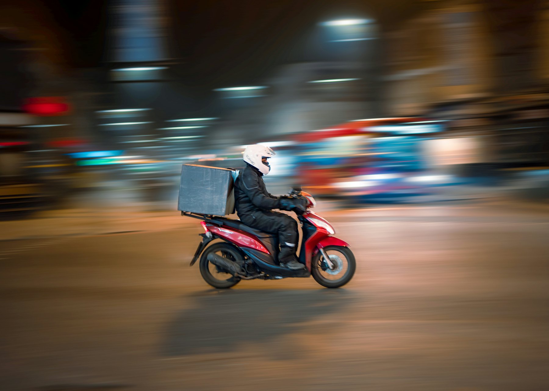 Gece şehirde paket teslimatına giden kurye